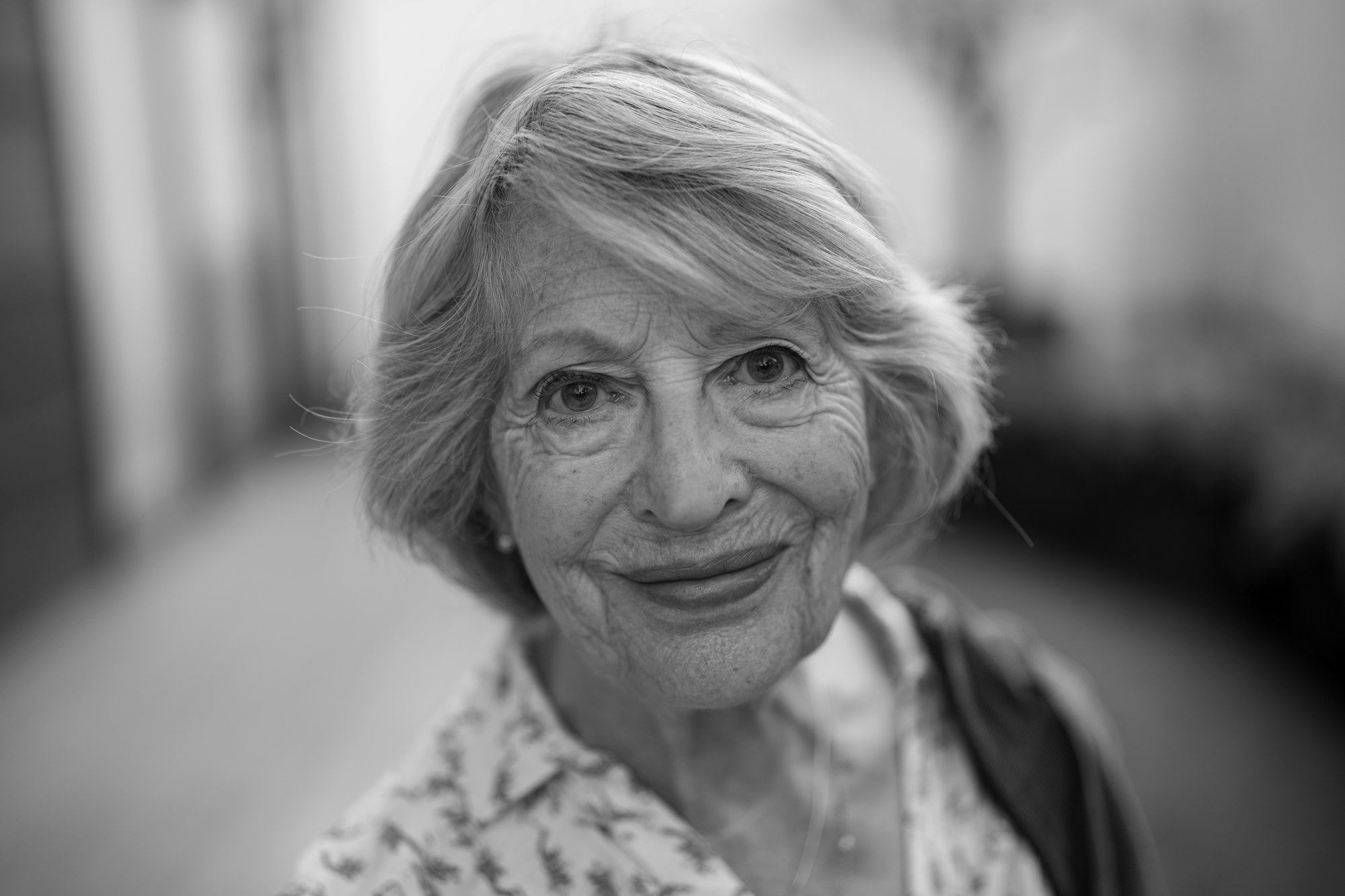 An older woman with silver hair smiling, photographed in black and white